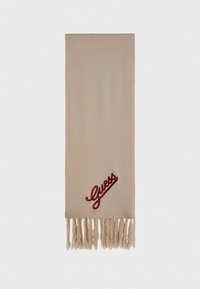 Écharpe beige en tissu doux, avec un logo "Guess" brodé en rouge et des bords fringés pour apporter texture et détail.