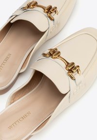 Mocassini slip-on in pelle beige con dettaglio in metallo dorato a forma di morso e soletta con marchio, suola piatta in legno e design della punta quadrata arrotondata.