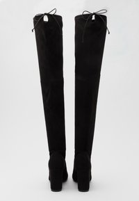 Botas altas negras de ante con textura suave, tacones cuadrados y lazos en la parte superior; diseño liso y elegante con detalles de costura sutiles.