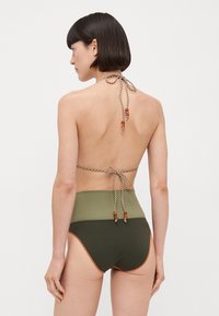 Bikini taille haute avec des panneaux vert olive et olive foncé, lien de cou tressé avec des accents en perles orange, texture lisse.