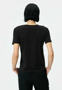 Sort bomulds T-shirt med korte ærmer, rund halsudskæring og en glat tekstur. Bagsiden har et klassisk snit og minimale designdetaljer.