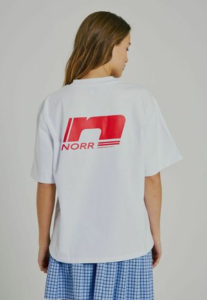 Weißes Baumwoll-T-Shirt mit kurzen Ärmeln, das auf der Rückseite ein großes rotes Logo "NORR" zeigt. Gerader Schnitt, lockere Passform, glatte Textur.
