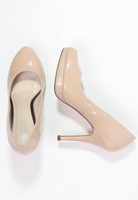 Beige patenterat läder högklackade skor med spetsig tå och en smal siluett, med en slät, glänsande yta och en smal stilettklack.