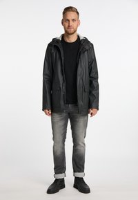 Sort vandtæt jakke med grå hætte, lynlåslukning foran og to knap-lukket lommer. Par grå jeans med opsmøg ved bunden og sorte sneakers.
