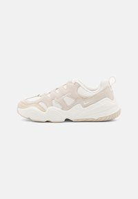 Sneaker sportivo con una tomaia testurizzata di un leggero beige chiaro realizzata in materiali mesh e suede, dettagli bianchi e una suola chunky e ammortizzata.