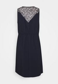 Mouwloze marineblauwe jurk met een kanten achterkant met een golvend patroon, elastische taille en een vloeiende silhouet.