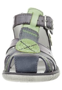 Nahkainen sandaali, jossa harmaita ja vihreitä sävyjä, avoin varvasmuotoilu, säädettävä solki ja kontrastiväriset ompeleet. Tasapohjainen kumipohja.
