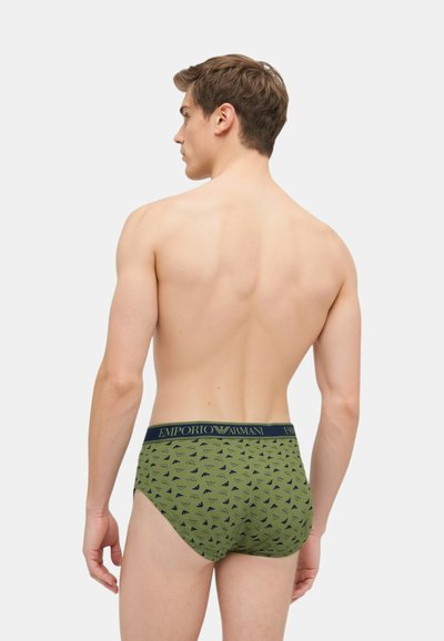 Slip in cotone verde con elastico nero Emporio Armani, caratterizzato da un motivo sottile con piccoli loghi blu navy. La vista posteriore mostra un design aderente.
