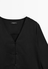 Zwarte longsleeve met V-hals, voorzien van drie decoratieve knopen aan de voorkant en een gladde, zachte textuur. Etiket: Massimo Dutti.