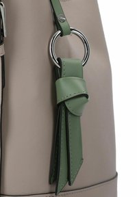 Borsa in ecopelle beige con un accento a nappina verde. Presenta un anello in metallo argentato e dettagli cuciti sulla nappina.