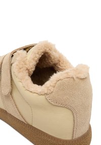 Barna velúr és bőr sportcipő puha bézs szegéllyel, tépőzáras pánttal és texturált barna gumitalppal.