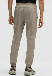 Lichte, beige sportbroek met een elastische tailleband en taps toelopende manchetten. Voorzien van ritsen aan de zijkanten en een gladde, duurzame stof.