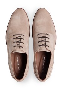 Μπεζ σουέτ παπούτσια με ομαλή υφή, στρογγυλεμένη μύτη και καφέ κορδόνια. Το εσωτερικό διαθέτει τυπωμένο λογότυπο και σκούρα σόλα.
