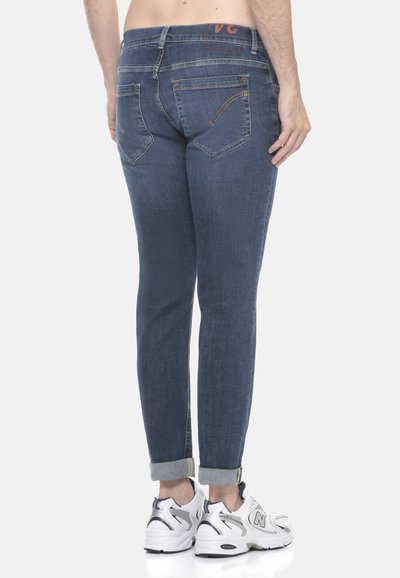 Jeans in denim blu scuro con vestibilità slim, dotati di vita media, orli piegati e cuciture arancioni a contrasto sulle tasche posteriori.