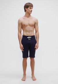 Μπλε ναυτικό μαγιό σορτσάκι από ελαφρύ ύφασμα, με ελαστική μέση με κορδόνι και μήκος μέχρι το γόνατο, με λεία υφή και μίνιμαλ σχεδιασμό.