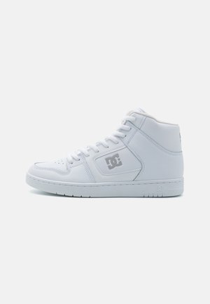 Basket blanche montante avec lacets, bout perforé et logo DC sur le côté, vue de profil sur un fond clair uni.