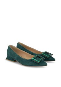 Zapatos planos de gamuza verde con punta afilada, que cuentan con una hebilla cuadrada decorativa adornada con piedras verdes y negras, y tacones cortos en bloque.