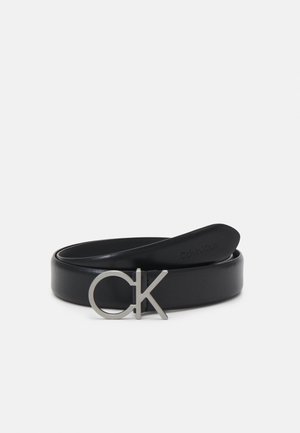 Zwarte leren riem opgerold met zilveren CK-logo gesp, minimalistisch ontwerp op een effen witte achtergrond.