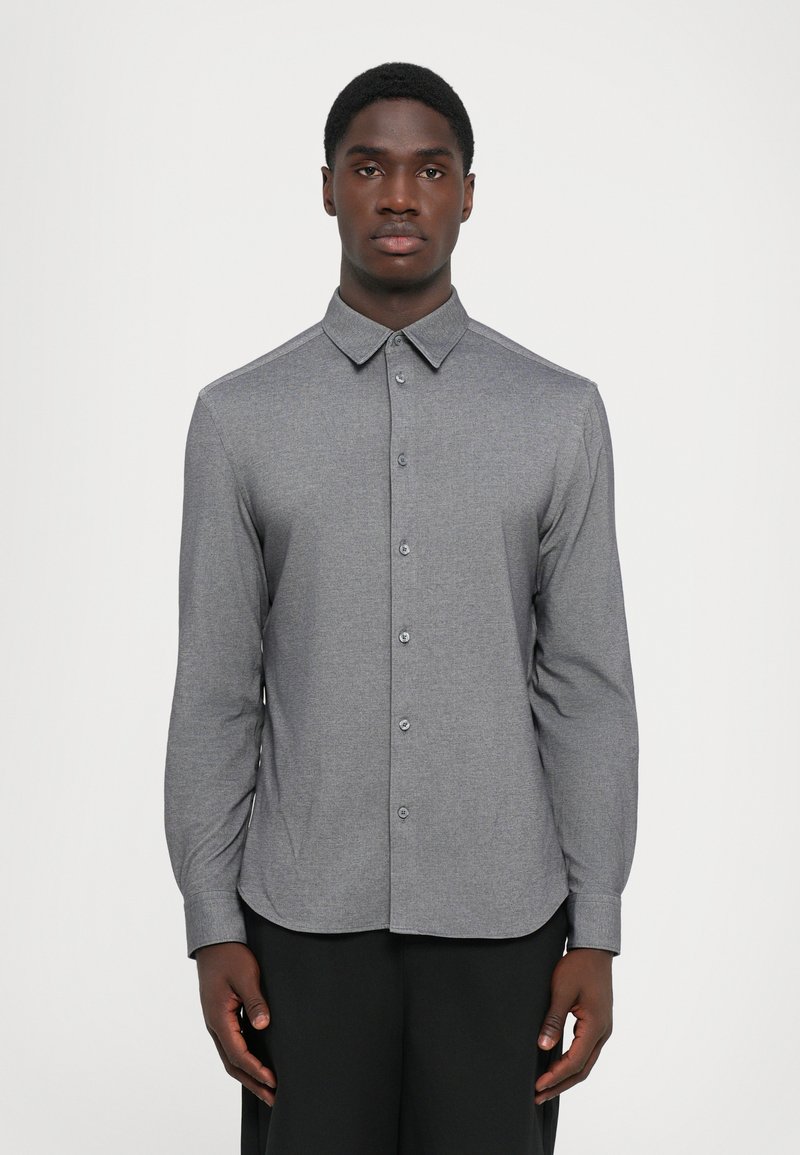 Camicia grigia a maniche lunghe con colletto button-down, tessuto testurizzato e orlo arrotondato. Presenta una chiusura frontale con bottoni e polsini standard.