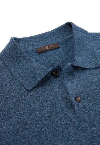 Niebieska teksturowana dzianinowa koszulka polo z dwoma ciemnymi guzikami i brązową metką z napisem "SLOWEAR ZANONE" wewnątrz kołnierzyka.