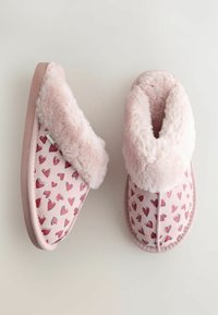 Roze slippers met pluizige zomen en suède materiaal, met een rood hartjespatroon. De zool is glad met het logo als detail.