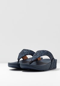 Flip-flops med en marineblå bunn, glitrende mørkeblå stropper med teksturert overflate, og en polstret såle.