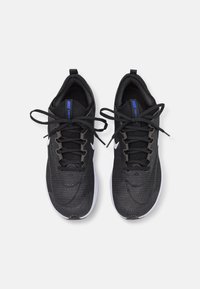 Paire de chaussures de course Nike noires avec semelles blanches et lacets noués en nœuds, vues de dessus sur un fond blanc.