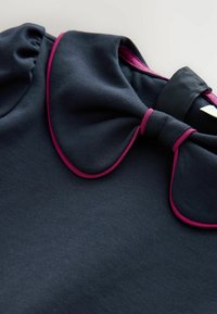 Vestito blu navy con colletto tondo impreziosito da piping rosa, dotato di maniche arricciate e una texture liscia e opaca.