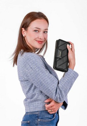 Černá kožená peněženka s prošívaným designem, zipovým uzávěrem a zlatými kovovými doplňky, držena proti bílému pozadí. Jaket z textilního vzoru.
