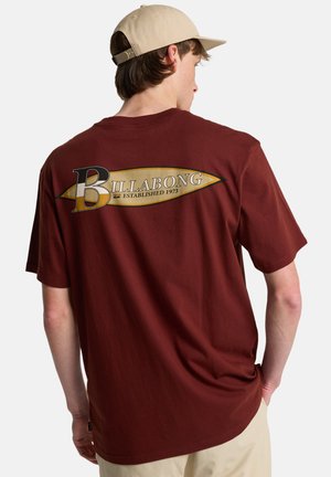 Bordowa bawełniana koszulka z krótkim rękawem, z dużym nadrukiem logo Billabong i datą założenia na plecach.