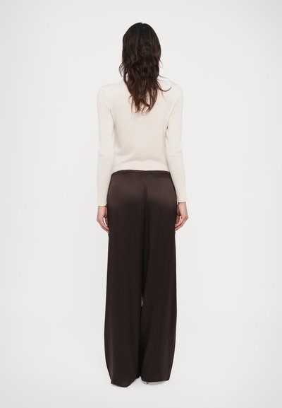 Cream long-sleeve top and brown wide-legged pants. The top is fitted; the pants feature a relaxed silhouette with an elastic waistband.
