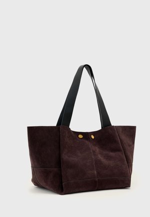 Τσάντα tote από καφέ σκούρο σουέτ με δύο μακριές μαύρες δερμάτινες λαβές και δύο μικρές χρυσές λεπτομέρειες με κουμπιά στο μπροστινό πάνελ.
