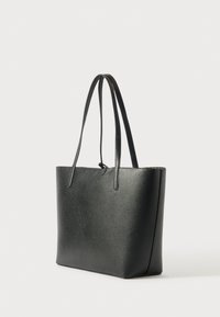 Čierna kožená taška s textúrou, s dvojitými ramennými popruhmi a malým zapínaním, vystavená na svetlom pozadí.