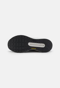 Semelle extérieure en caoutchouc noir avec texture à motifs, présentant une semelle intermédiaire blanche et un petit logo jaune "GOODYEAR".