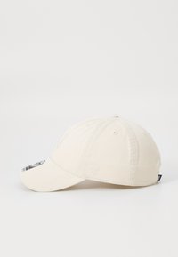 Beige baseballcap med broderede logoer, buet skygge og seks-panel design. Fremstillet af tekstureret stof med ventilationshuller.