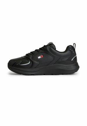 Sort lavskaftet sneaker med snørelukning, tyk sål, trækstrop ved hælen og lille rød, hvid og blå logo på siden.