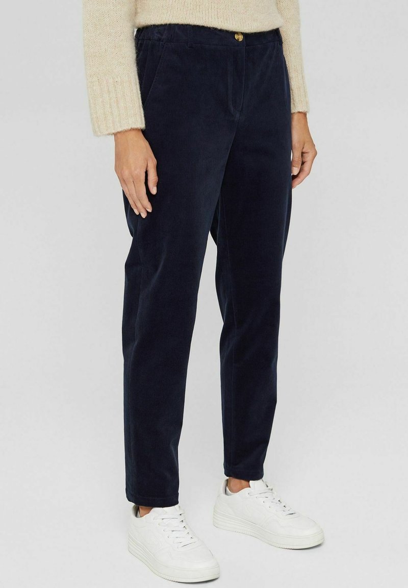 Marineblaue Cordhosen mit einer lockeren Passform, ausgestattet mit einem Knopfverschluss und seitlichen Taschen, kombiniert mit weißen Sneakers. Weiche Textur, gerades Bein Design.