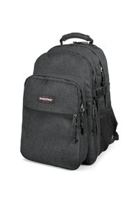Mochila de tela negra con múltiples compartimentos con cremallera, respaldo acolchado, correas ajustables y un bolsillo lateral de malla. Logo de Eastpak en la parte frontal.
