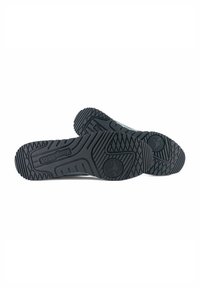 Scarpe da ginnastica nere in gomma con suole testurizzate che presentano un motivo di battistrada per migliorare la trazione e un dettaglio con logo sul tallone. Progettate per resistenza e supporto.
