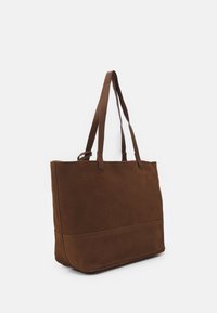 Brun läder tote-väska med två långa axelremmar och en slät, enfärgad yta, visas mot en vit bakgrund.