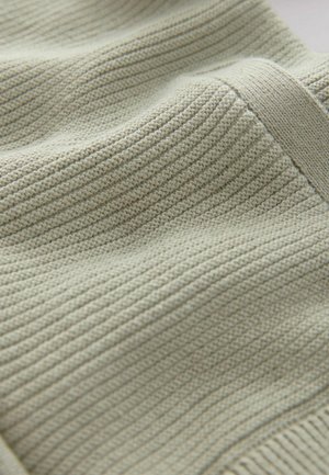 Hellgrüner gestrickter Stoff mit einem strukturierten, gerippten Muster. Glattes, weiches Material fällt sanft und zeigt subtile Farbvariationen.