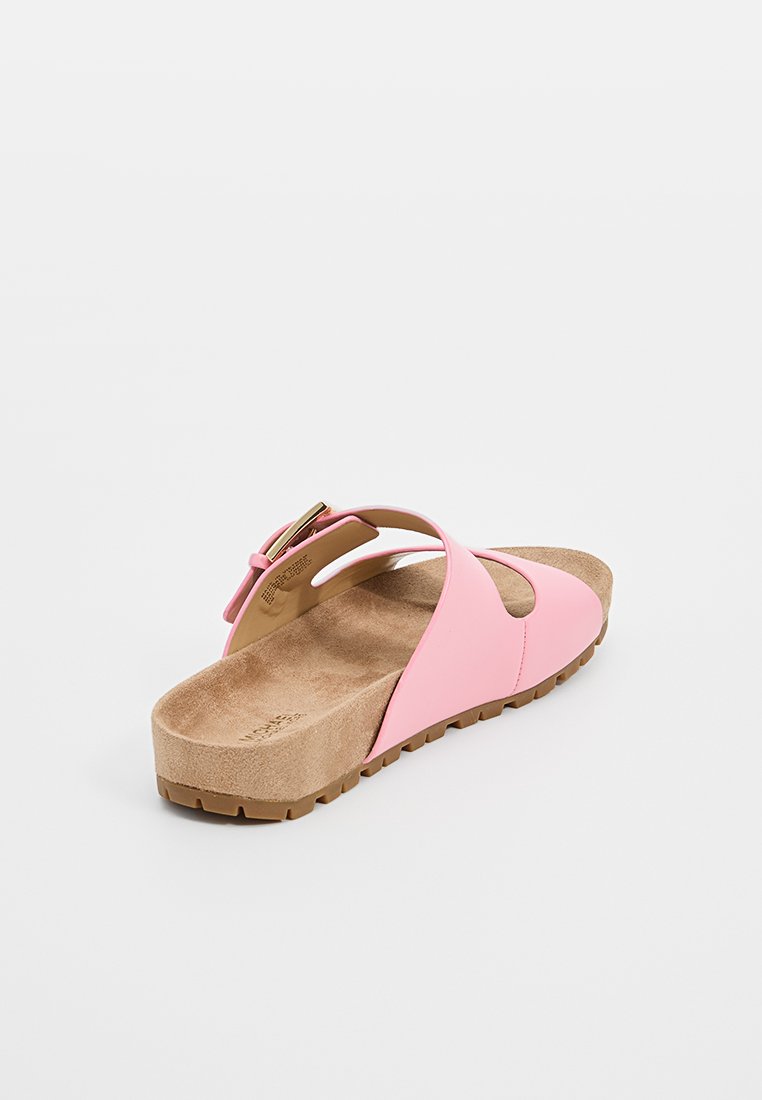 Sandale à semelle en daim rose avec une sangle réglable et boucle dorée, ainsi qu'une semelle en caoutchouc texturée, sur fond blanc.