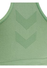 Zielona sportowa bluzka bezszwowa z dwoma wypukłymi wzorami typu chevron oraz widocznymi przeszyciami na górnej części pleców.
