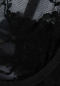 Svart spets tyg med ett blommönster, som har en texturerad nätstruktur och solid svart kant längs kanterna.