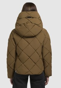 Bruine doorgestikte pufferjas met een grote capuchon. Kenmerken zijn een ruitpatroon, gladde textuur en een label aan de achterkant nabij de halslijn.