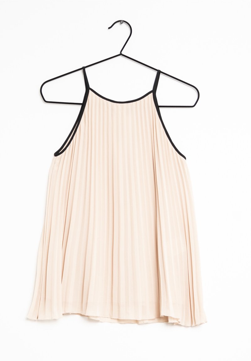 Robe plissée sans manches beige clair avec une fine bordure noire sur les bretelles et l'encolure, suspendue à un cintre en métal noir sur fond blanc.