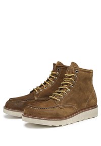 Stivali a metà gamba in suede marrone con lacci gialli, punta stile mocassino, suola in gomma bianca a contrasto e dettagli di cucitura laterale.