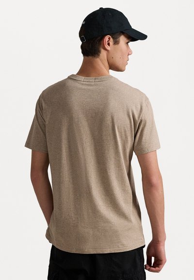 Καφέ κοντομάνικο μπλουζάκι φτιαγμένο από μαλακό ύφασμα, με στρογγυλή λαιμόκοψη και άνετη εφαρμογή, εμφανίζεται από πίσω με ελάχιστες λεπτομέρειες.