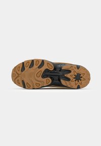 Black and gum rubber sneaker sole featuring an intricate tread pattern and accentuated curves for traction and support.