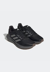 Czarne sportowe buty z teksturowaną siateczką na cholewce, z trzema srebrnymi paskami, wyściełanym kołnierzem i gumową podeszwą.